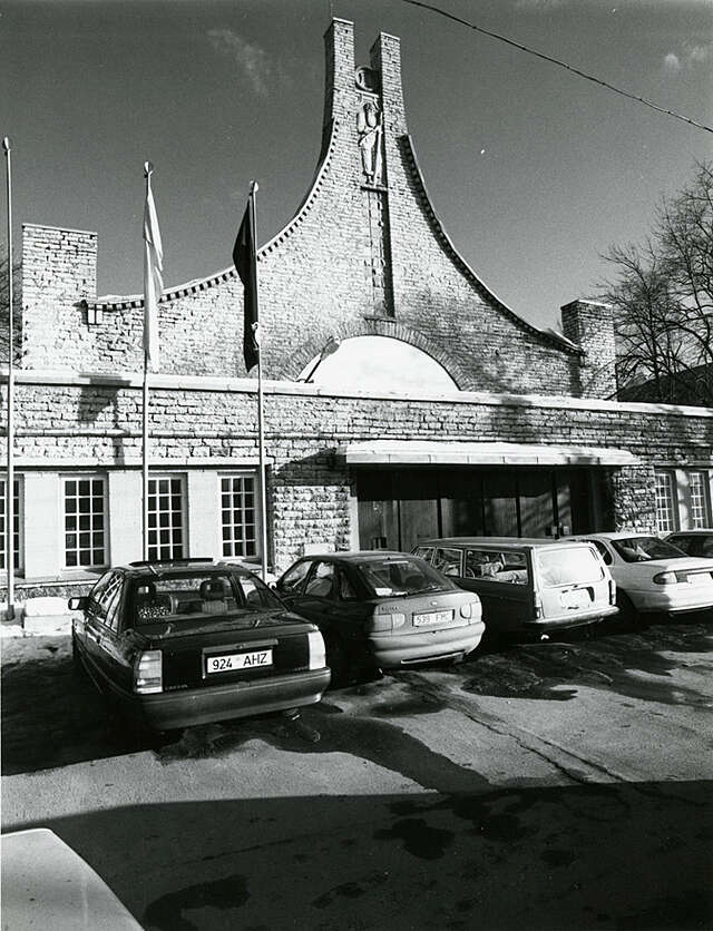 Old brick facade with cars in front of the building on an black and white picture.
