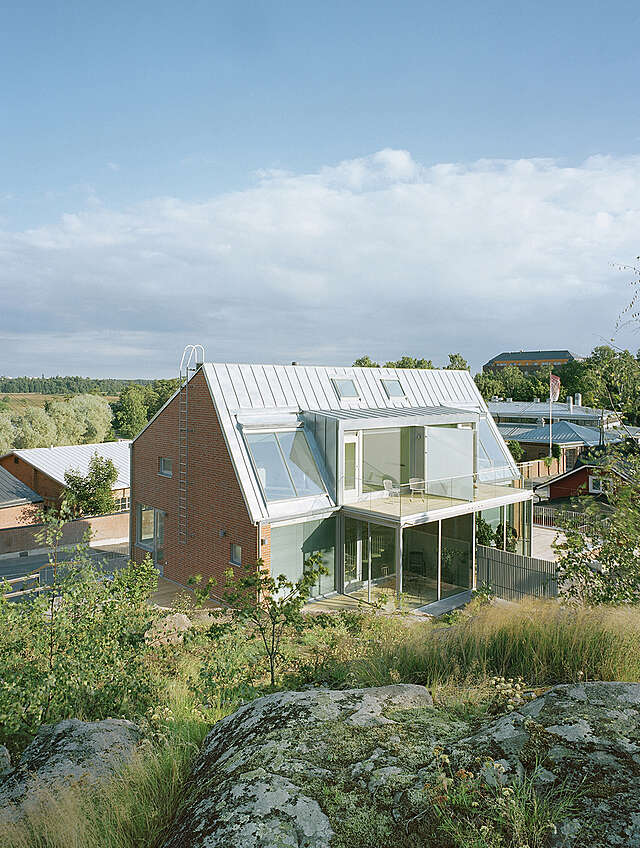 Semi-detached brick house with large windows and a protruding balcony.