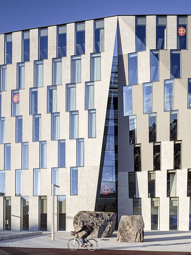 Office facade with beige stone walls and tall and narrow windows in an offset pattern.