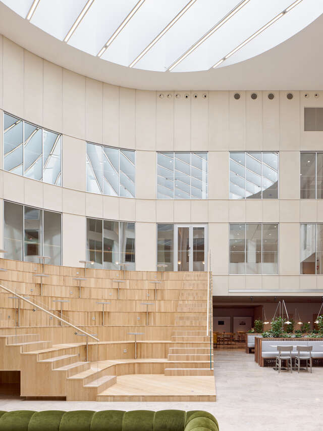 A large, wooden seating area in a large room with a skylight.