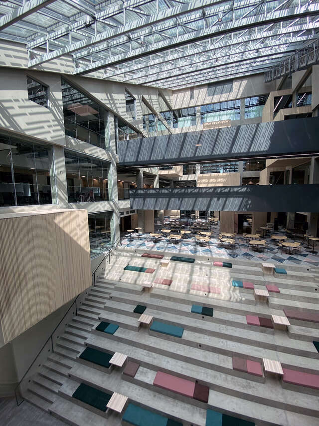 A large room with a large staircase where people can sit and a large glass roof