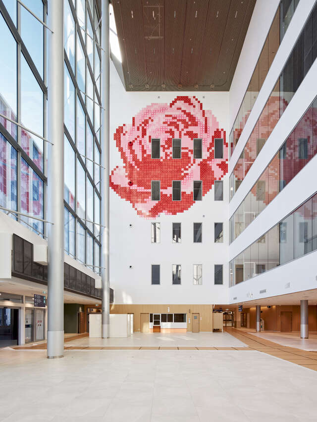 Interior view of a large-multi story building's lobby. A large red artwork is seen on the far wall.