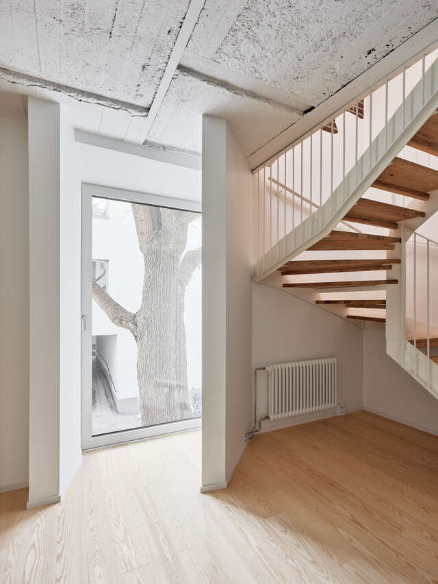 A large window to a courtyard as seen from inside. Wooden staircase on the right.