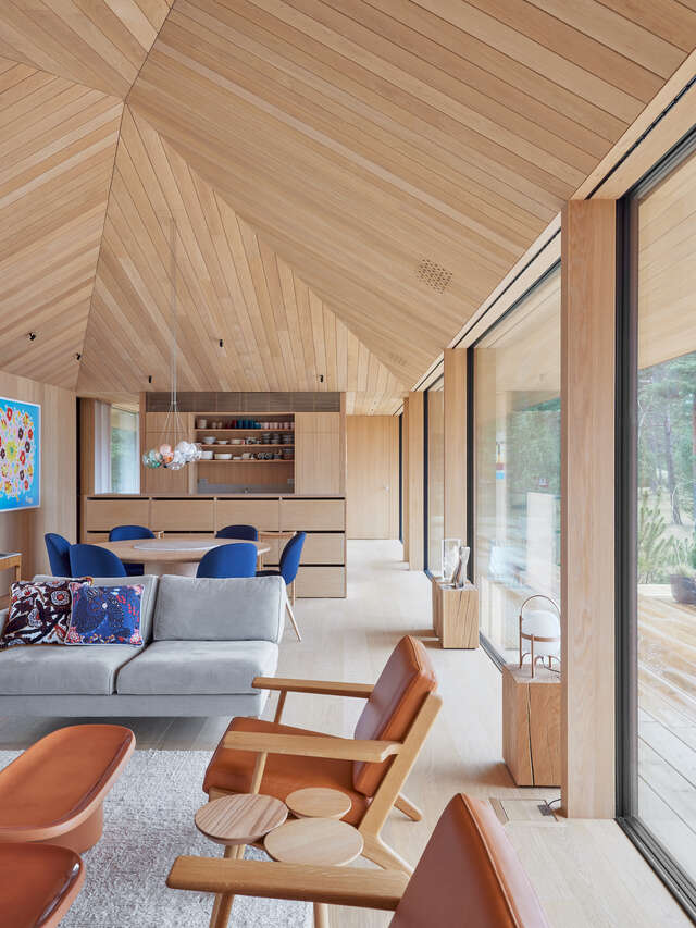 A large room with couches and chairs in the foreground and a kitchen in the background.