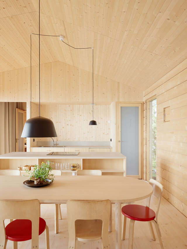 A wooden indoor space with a kitchen and a dining table.