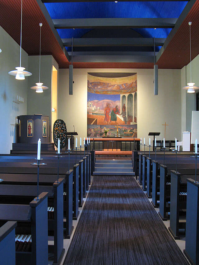 View from black benches to the altar, the ceiling is illuminated blue.