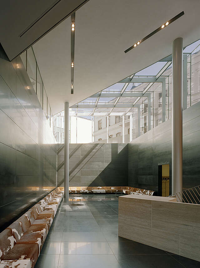 Entrance hall with a wooden reception desk and leather bench extending over three sides of the room.
