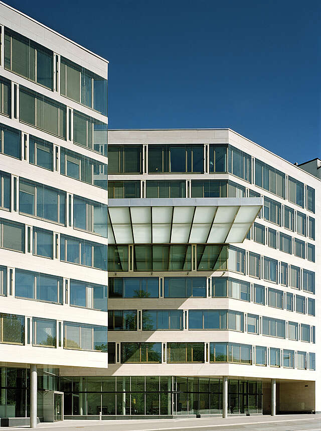 Facade of the Pension Fund Office Building with light yellowish natural stone and large windows.