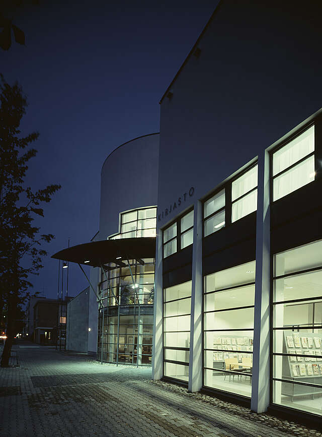 Library facade during the night with light coming from the large windows.