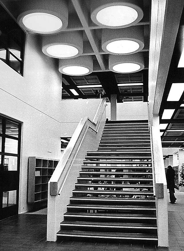 Staircase with white railings and six large circular lights above it.