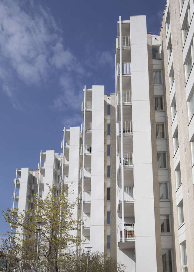 Stepped apartment buildings with brown tile and white panel elements.