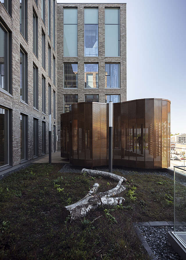 Free-form pavilion coated with copper mesh on a green rooftop terrace