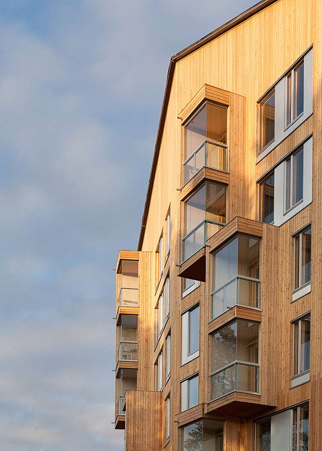 Apartment building with a wooden exterior, a gable roof and protruding balconies.