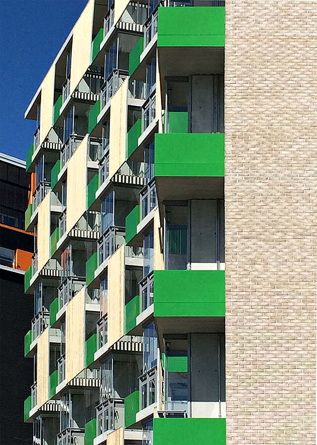 Multiple storey apartment building with green balconies.