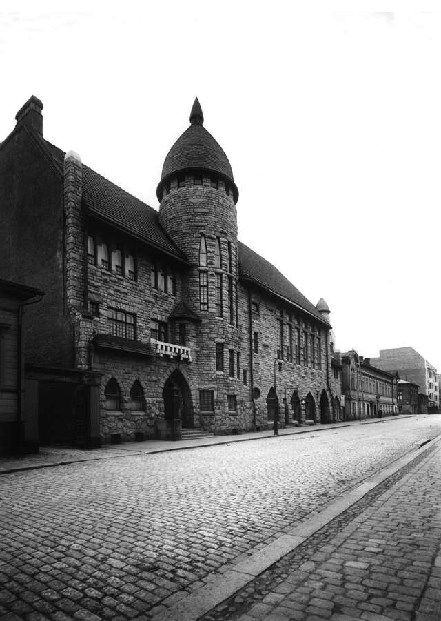 Black and white picture of a cobblestone street with an old stone building.