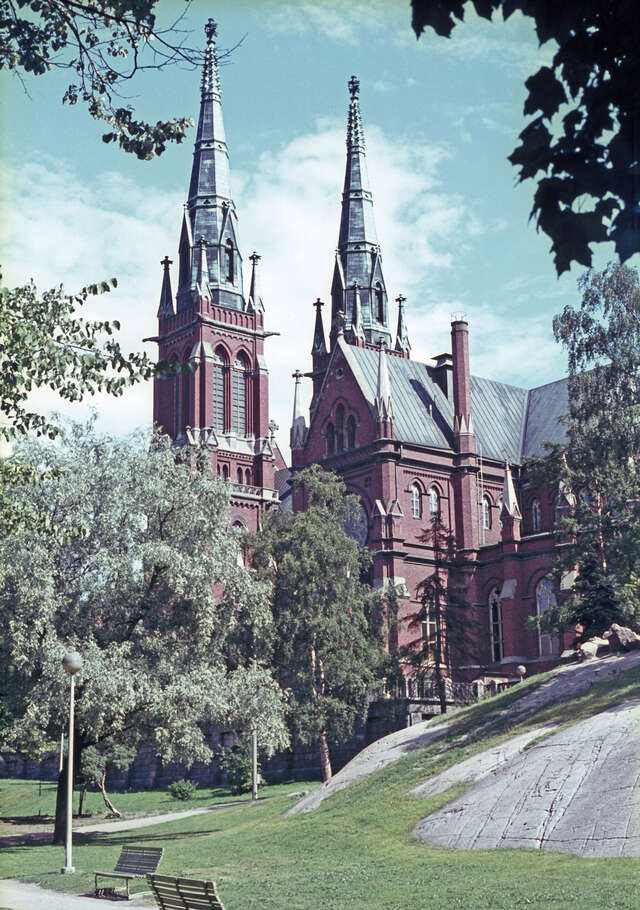 Gothic-style church with two towers, trees and rock