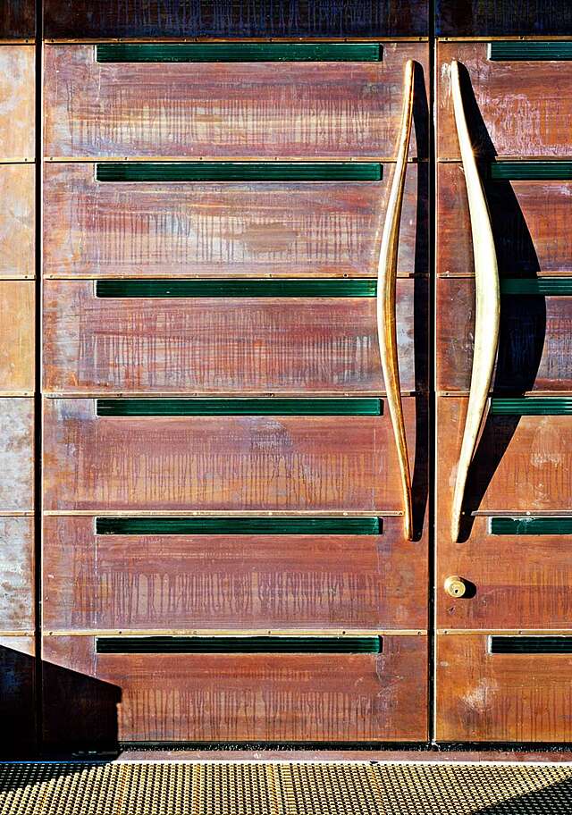 Rustic entrance doors with curved golden doorhandles.