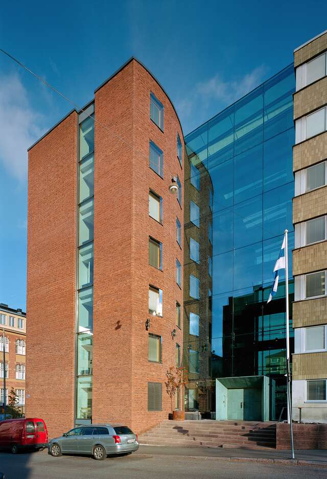 Red-brick end and glass part of the building above the copper green entrance