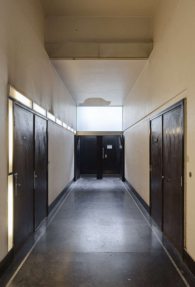 Hallway with cream colored walls and dark doors.