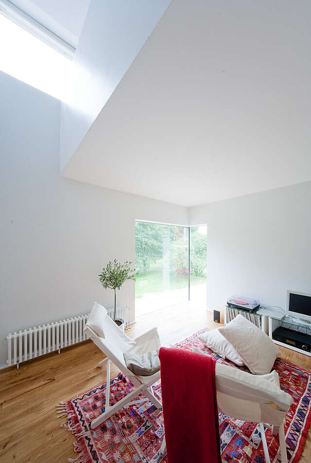Living room with a corner window and a cozy sitting area with white and red textiles.