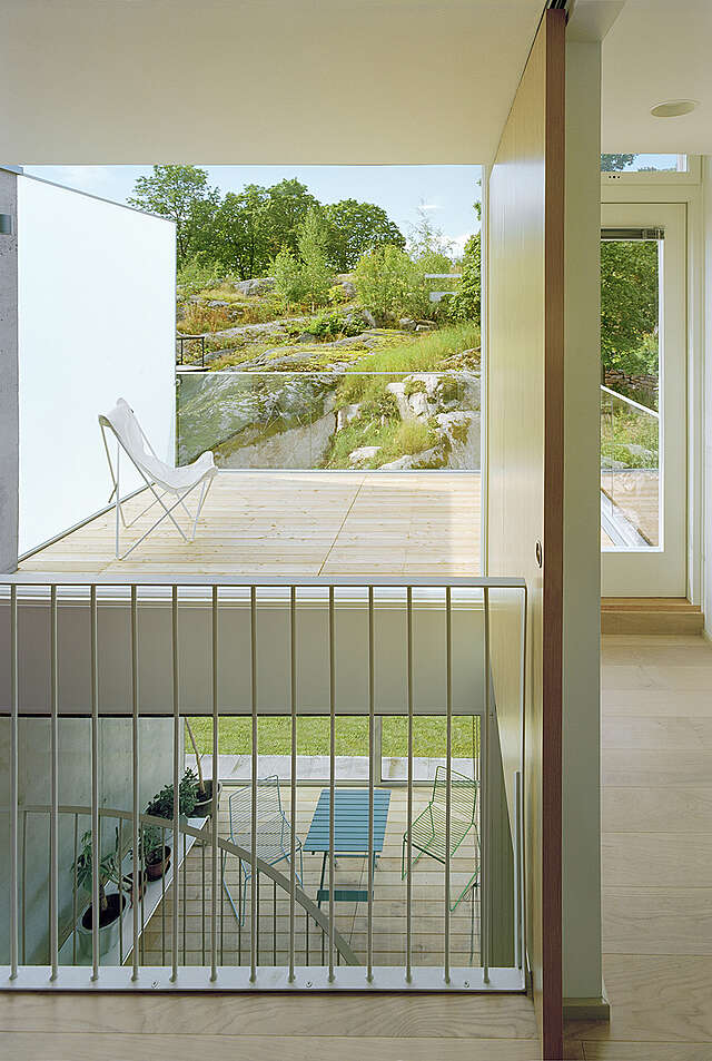 The balcony and the rocky landscape is visible from the stairway through a glass wall.