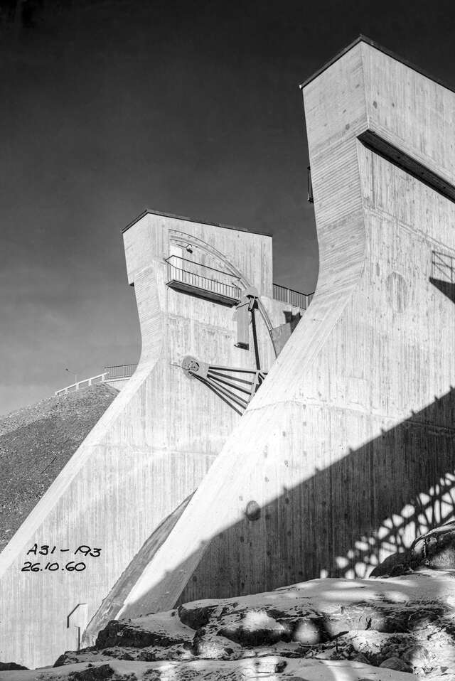 Black and white picture of the monumental, concrete spillway openings in the summer.