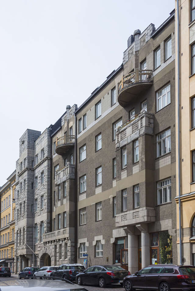 Block of flats with decoratons and balconies, cars in front of it