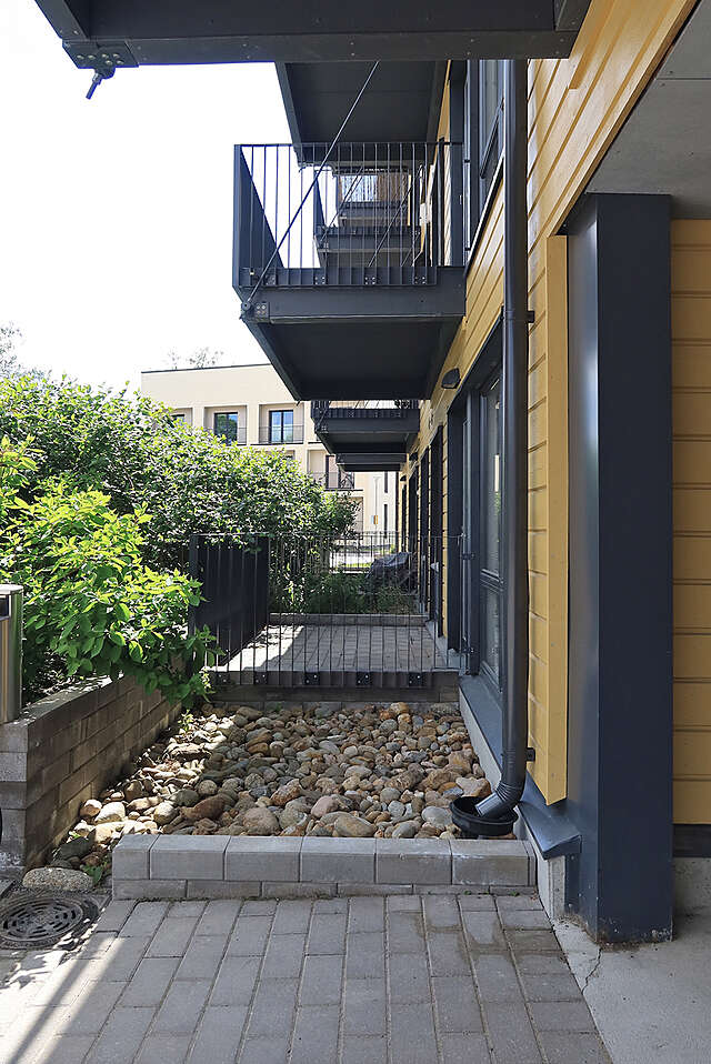 Close-up along a yellow facade with black balconies.