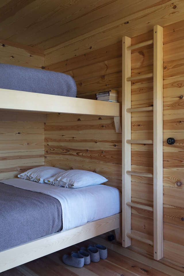 A two-storey bunk bed inside a wooden cabin.