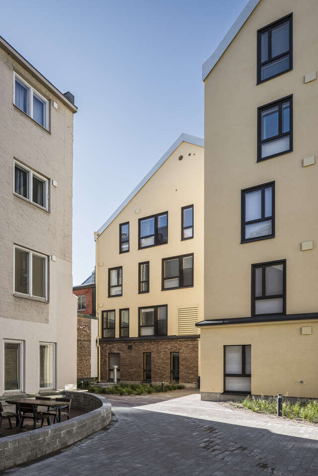 Courtyard of three yellow apartment buildings. A small ray of sunshine is lighting a part of the courtyard.