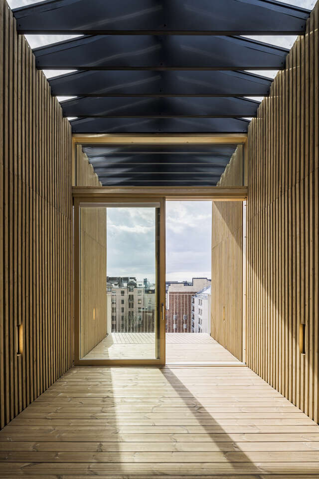 A wooden hallway leading out to a balcony through glass doors.