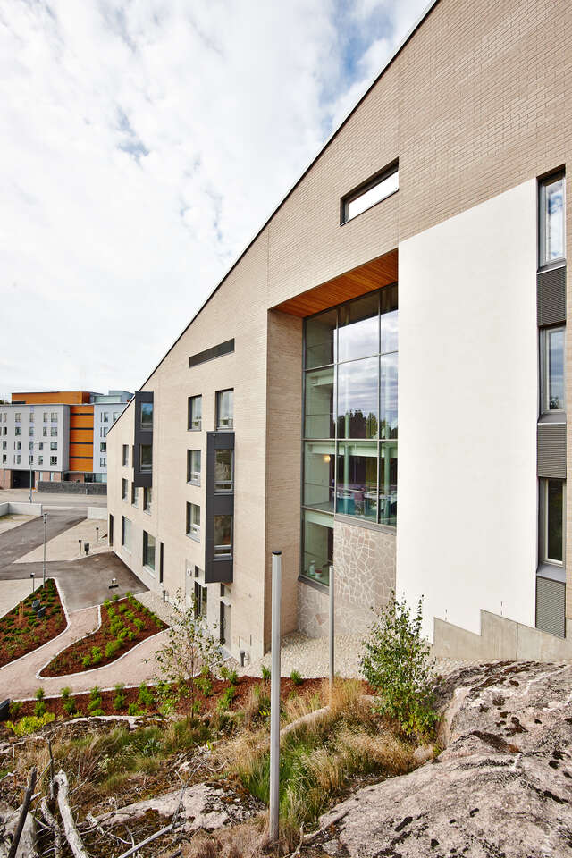 Beige tile facade with large window and a slanted roof.