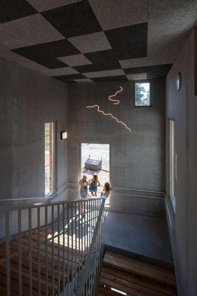 A staircase in a concrete stairwell. Three people looking out of a window.