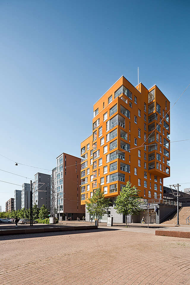Orange multiple storey apartment building with glass covered balconies.