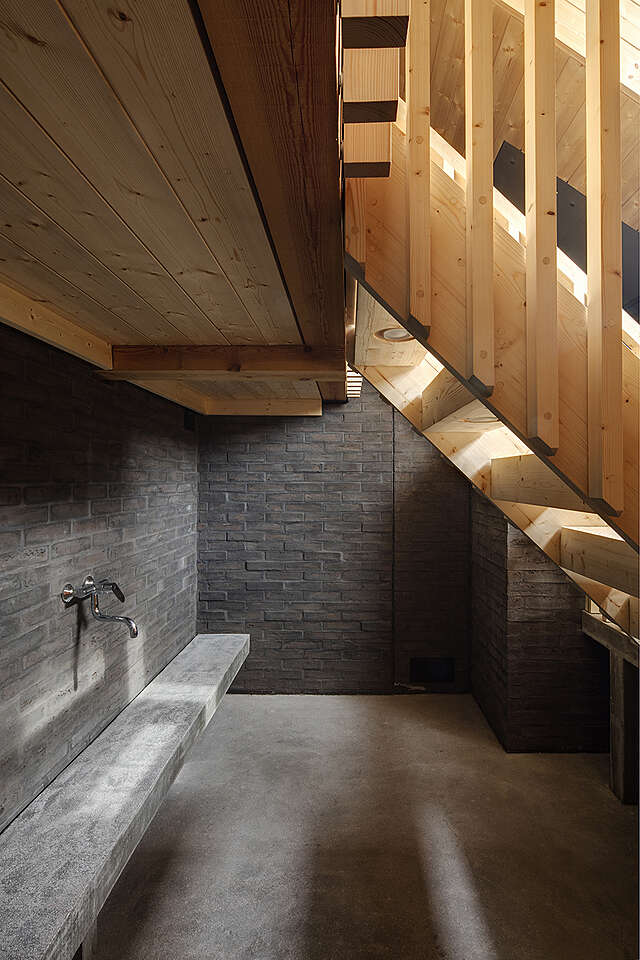 Dark wash area with stone walls and wooden stairs rising above it.