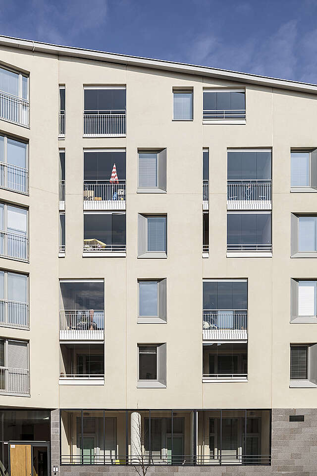 Close up shot of a beige plastered modern apartment building with a slanted roof.
