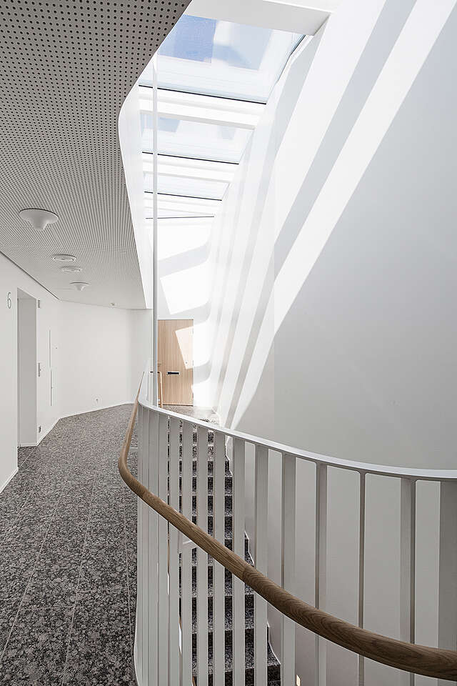 Stairway with a ceiling window and white and wooden railings.