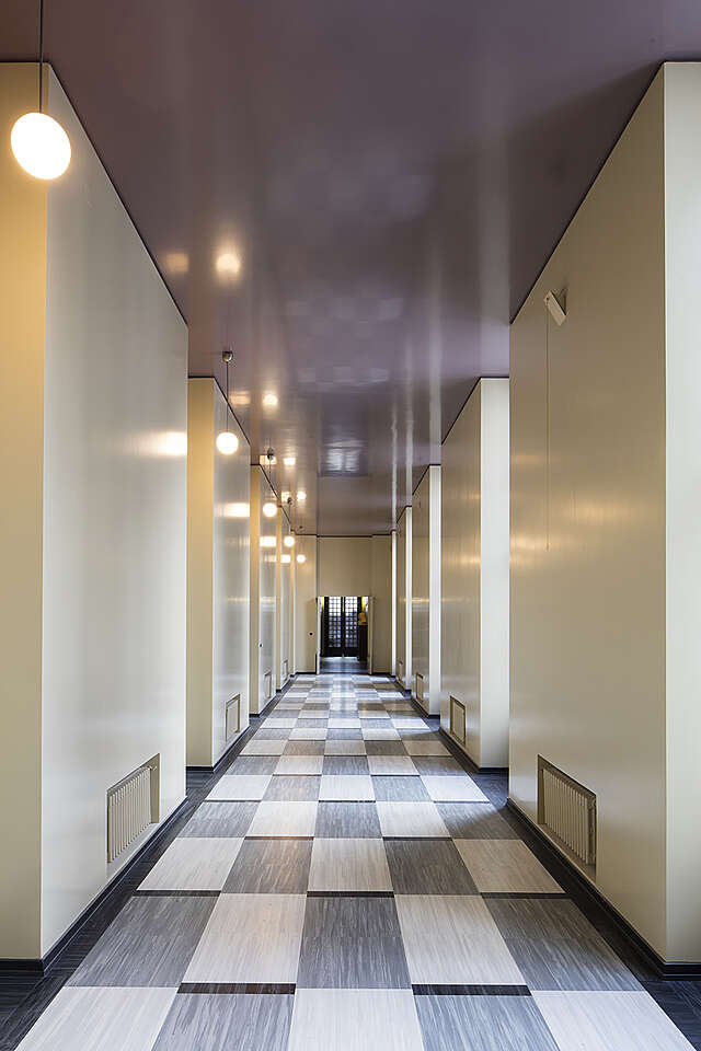 Hallway with a checkered floor and lavender ceiling.