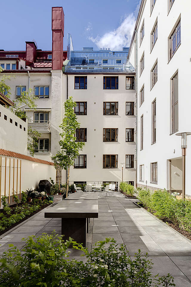 Green courtyard surrounded by white apartment buildings.