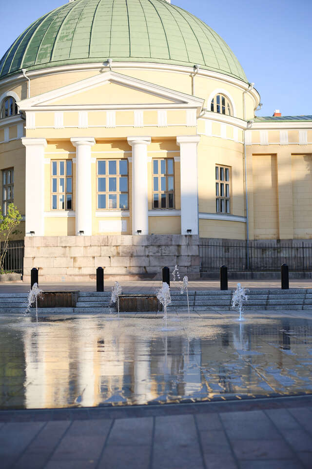 A small water fountain in front of an old stone building.