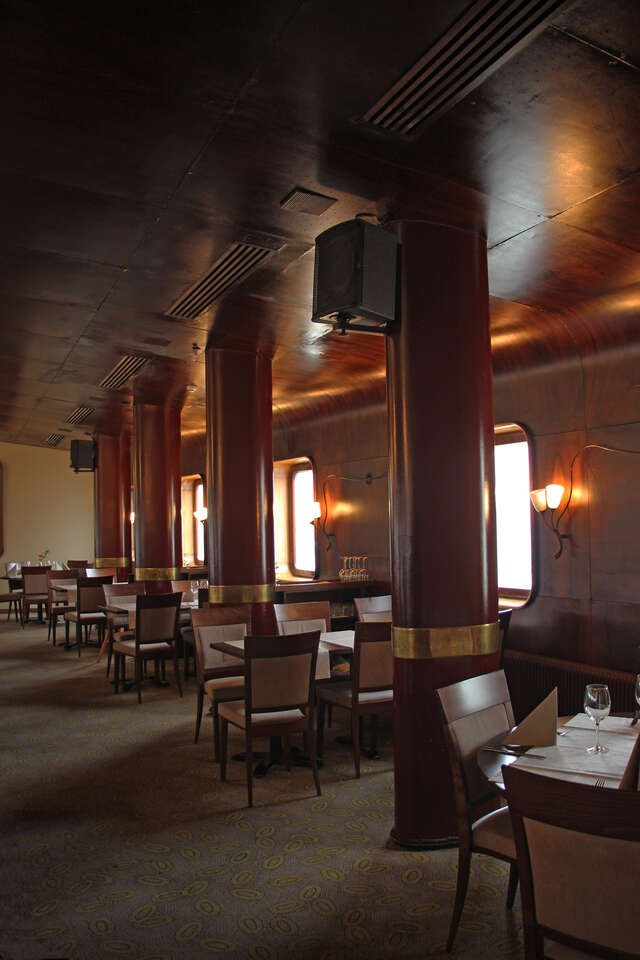 Dark and warm toned restaurant interior with red stone pillars and curved dark brown walls and ceilings.