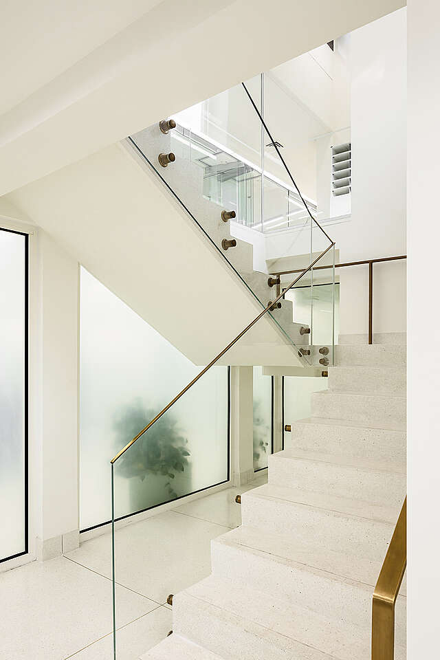 White marble staircase and a glass railing.