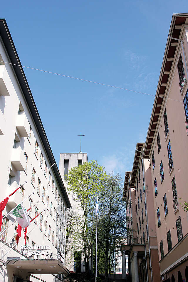 White multiple story building to the left and terra-cotta building to the right.