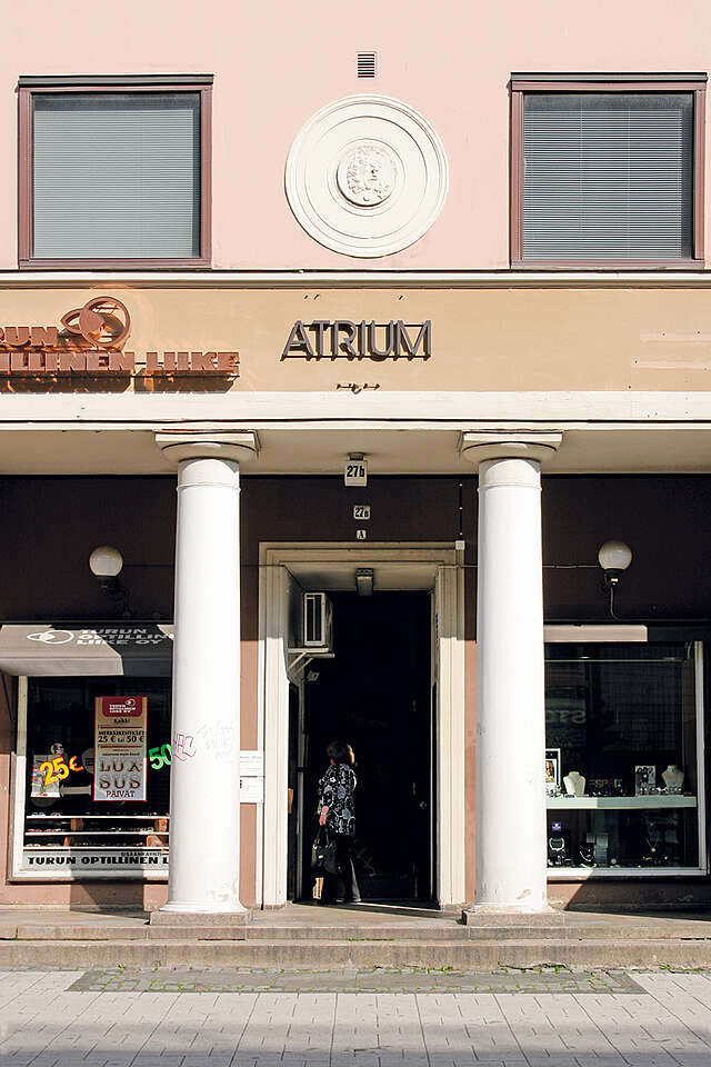 Entrance to the atrium with two pillars and shops on both sides.