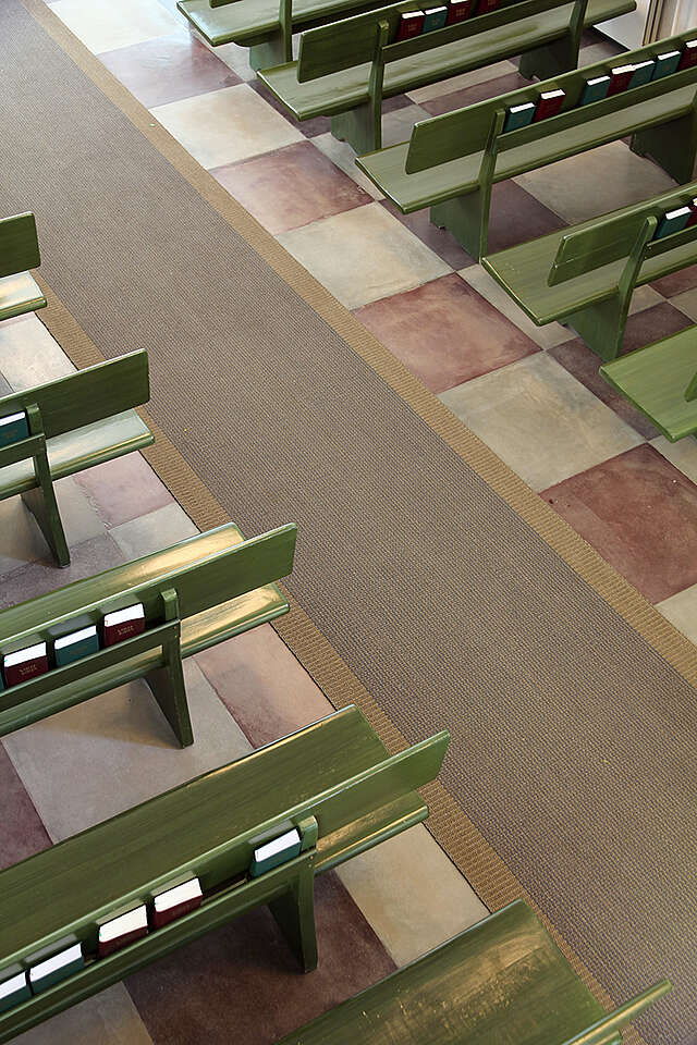 Red and white checkered floor, forest green benches and a grey carpet along the aisle.