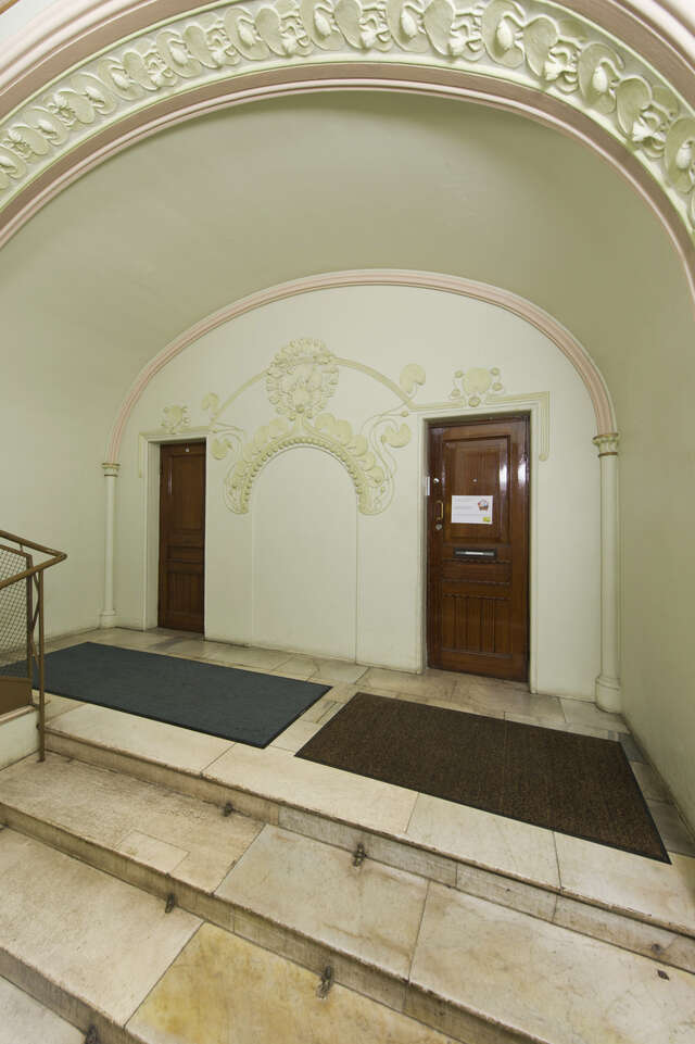 Top of the stairs with an arched being and two wooden doors.