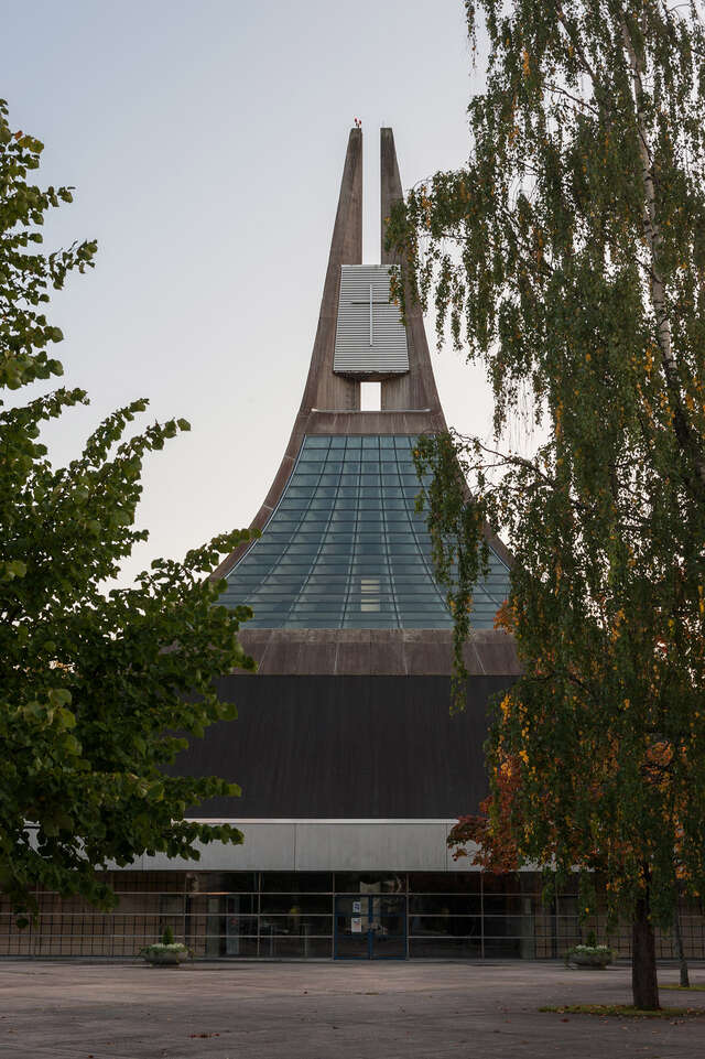 Concrete church behind birch trees