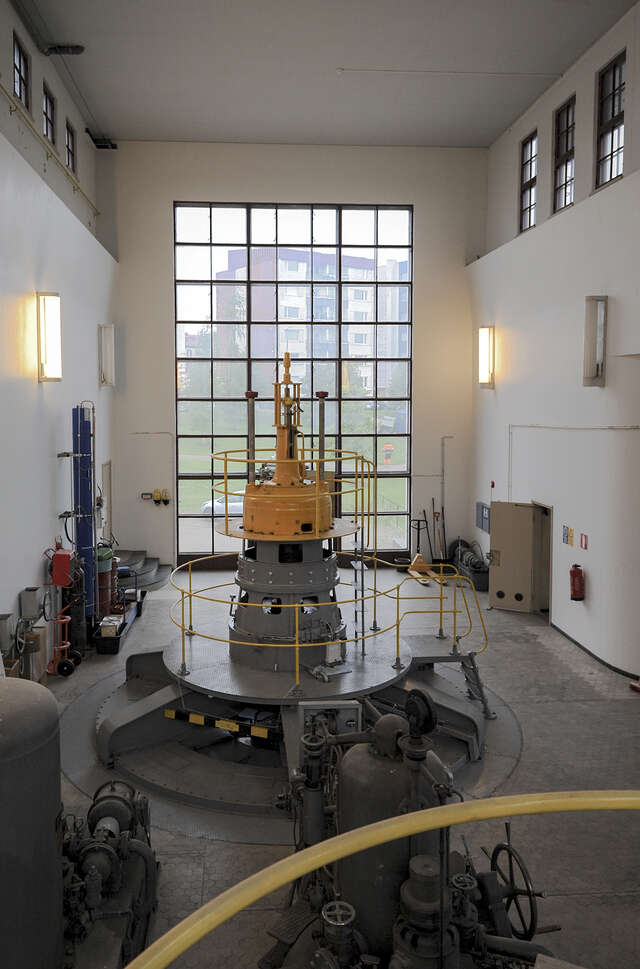 Photo from the machine hall with a high window that is divided in several smaller square shaped windows separated with thin window frames.