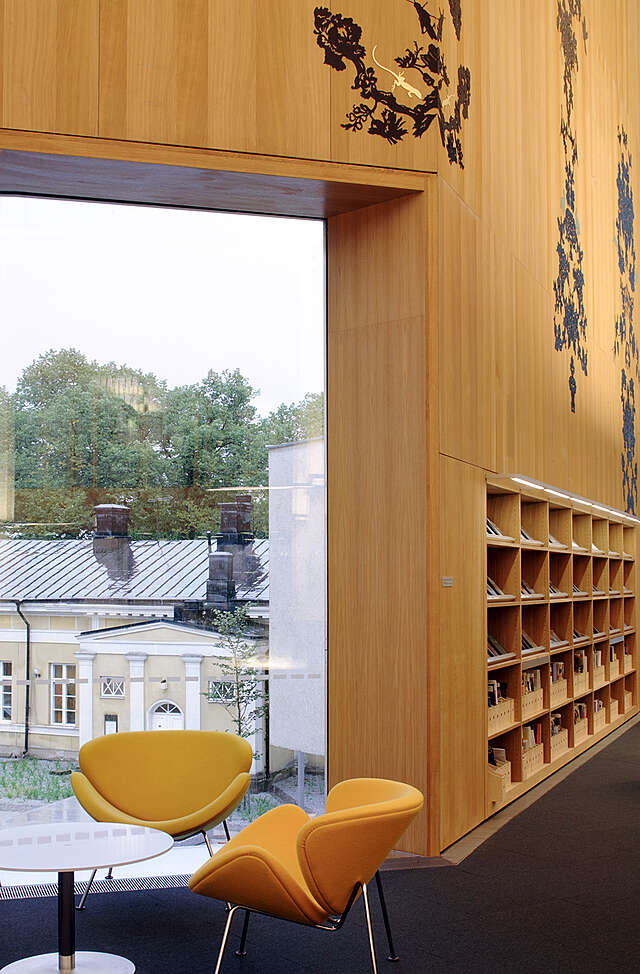 Reading nook next to a window with a wooden wall behind it.