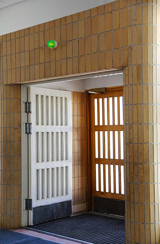 Wooden entrance doors are framed by yellow tiles.